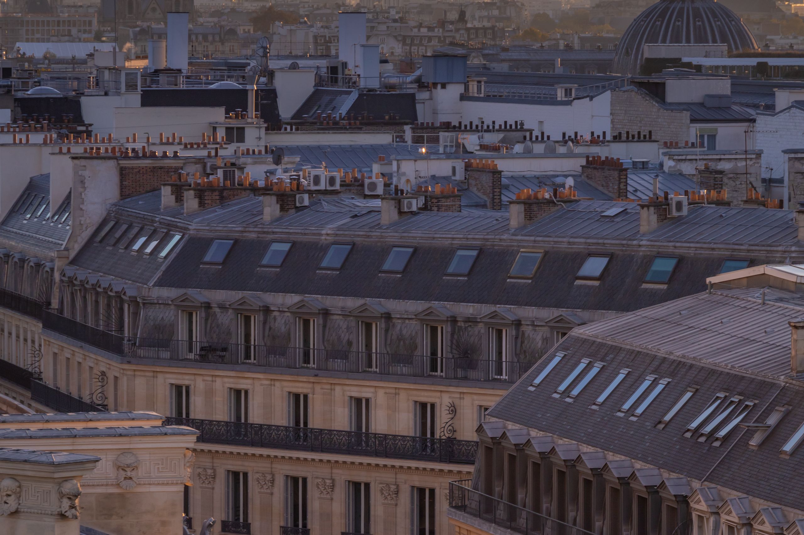 Vue en hauteur sur les toits de zinc de Paris au coucher du soleil